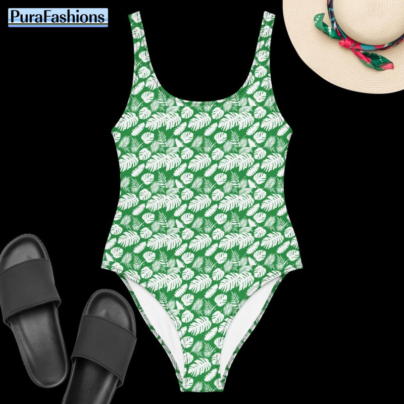 "Tropical bliss: PuraFashions.com introduces a one-piece swimsuit adorned with a lively tropical leaves pattern on a tranquil sea green background, laid flat to display its captivating design and beach-ready allure."