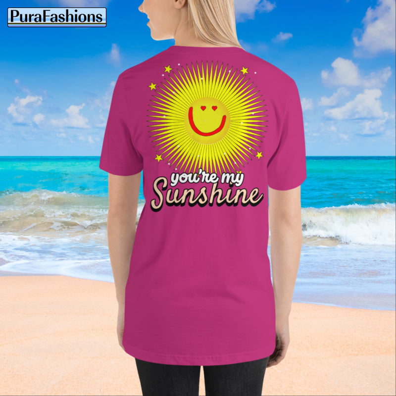 A woman wearing a berry red T-shirt with a large happy face sun and stars, and the text "You're My Sunshine" on the back. The front features a small happy face sun and stars. The image shows the back view. Available at PuraFashions.com.