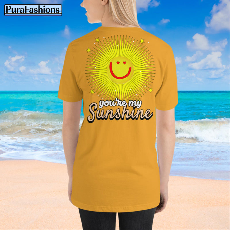 "Back view of a woman wearing an mustard yellow T-shirt with a large happy face sun and a few stars, along with the text 'You're My Sunshine'. The T-shirt has a small happy face sun and stars on the front as well. Available at PuraFashions.com."
