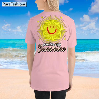 "Back view of a woman wearing an pink T-shirt with a large happy face sun and a few stars, along with the text 'You're My Sunshine'. The T-shirt has a small happy face sun and stars on the front as well. Available at PuraFashions.com."