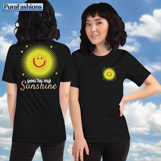 A woman wearing a black T-shirt featuring a large happy face sun and stars with the text "You're My Sunshine" on the back, and a small happy face sun and stars on the front. Both sides of the T-shirt are shown. Available at PuraFashions.com.