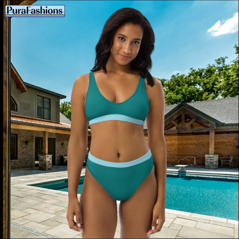 "A woman stands stylishly by the pool in a teal high-waist bikini accented with light blue trim, a fashionable choice from PuraFashions.com."